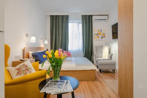 a living room with a bed and a vase of flowers on a table at Cosy and Stylish Studio next to Sofia's Central Market Hall in Sofia