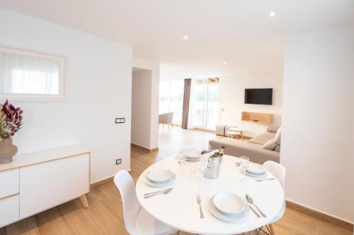 a white kitchen and living room with a white table and chairs at Apartamentos Blanco Sol in Cala Vadella