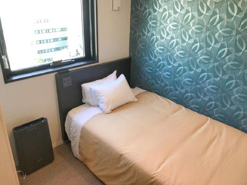 a small bedroom with a bed and a window at HOTEL LiVEMAX Ikebukuro Ekimae in Tokyo