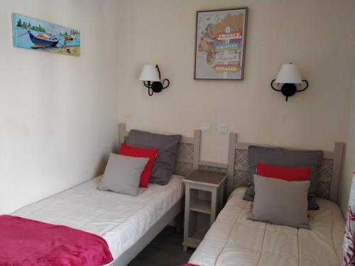 2 Betten in einem Zimmer mit 2 Lampen an der Wand in der Unterkunft Les Coteaux B10 in Mallemort