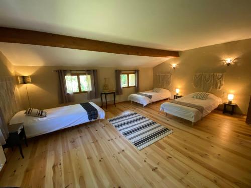 a large bedroom with two beds and wooden floors at Gîte le Moulin Samsara in Homps