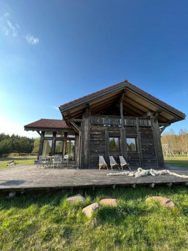 une cabane en rondins avec des chaises sur une terrasse en bois dans l'établissement Stella, à Ziemupe