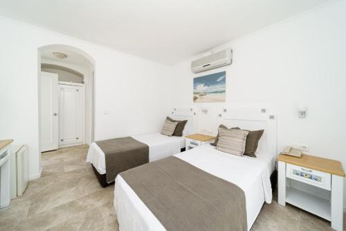two beds in a room with white walls and wooden floors at Costa Sariyaz Hotel Bodrum in Bodrum City