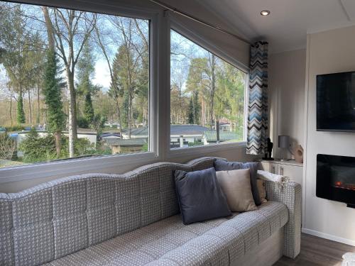 salon z kanapą i dużym oknem w obiekcie Luxe Chalet Hoenderloo Airco, Netflix - Recreation Only w mieście Hoenderloo