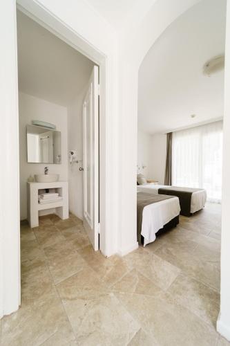 a white bedroom with two beds and a mirror at Costa Sariyaz Hotel Bodrum in Bodrum City