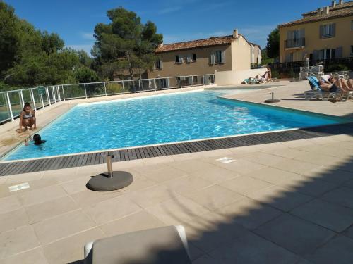 une grande piscine avec des chaises assises en face d'un bâtiment dans l'établissement Les Coteaux B10, Maison T3 climatisée dans le domaine du golf de Pont Royal, 6 pers maxi, à Mallemort