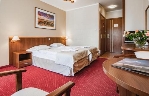ウェバにあるHotel Nadmorskiのベッドとテーブルが備わるホテルルームです。