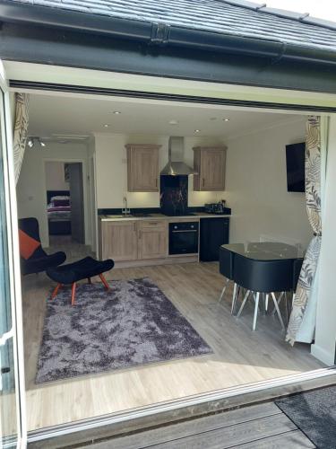 a living room with a table and a kitchen at Glenwood luxury Cottage Betws-y-coed in Betws-y-coed