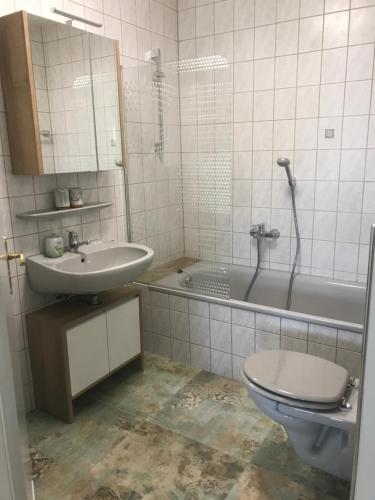 a bathroom with a toilet and a sink and a tub at Apartment Sioux in Eging