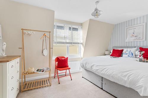 a bedroom with a large bed and a red chair at Captains Cottage - Stylish cottage, level location, in the heart of Dartmouth in Dartmouth