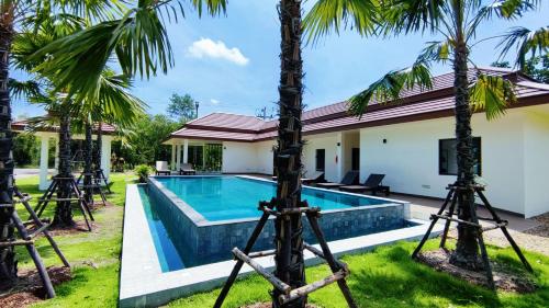 a villa with a swimming pool and palm trees at Isan Golf & Adventure Hotel in Udon Thani