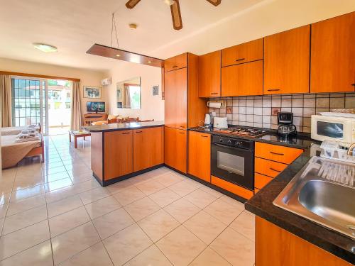a large kitchen with wooden cabinets and a sink at Colonial Studio/Apartment in Faliraki