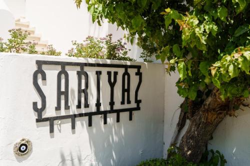 a sign on a white wall next to a tree at Costa Sariyaz Hotel Bodrum in Bodrum City