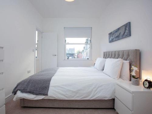 a white bedroom with a large bed with a window at 1 primrose mews in Torquay