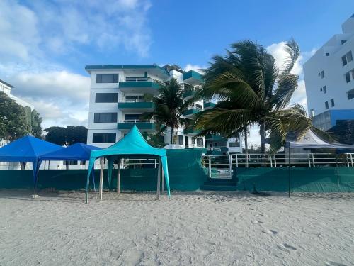 a group of blue tents on a beach with a building at Beachside apartment with 2 pools, Same, Esmeraldas in Volcán Chimborazo