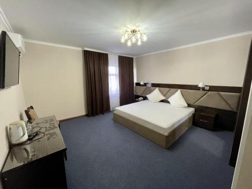 una habitación de hotel con una cama y un televisor en Comfortplace, en Atyraū