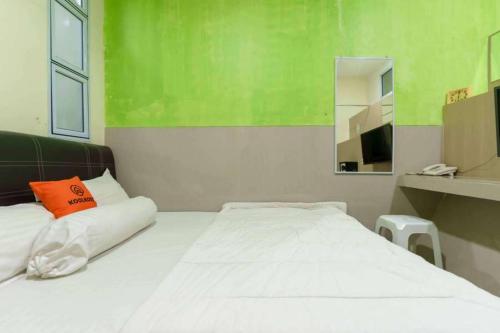 a bedroom with a white bed with an orange pillow at KoolKost near Nagoya Hill Batam (Minimum Stay 30 Nights) in Nagoya