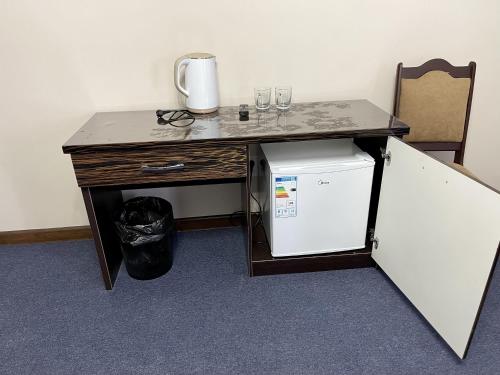 a desk with a small refrigerator next to a table at Comfortplace in Atyraū