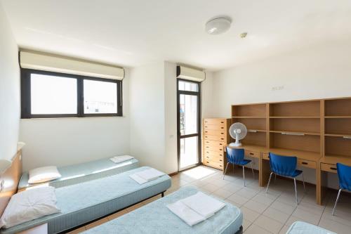 a room with a bed and a desk and chairs at Ostello Ipsia in San Benedetto del Tronto