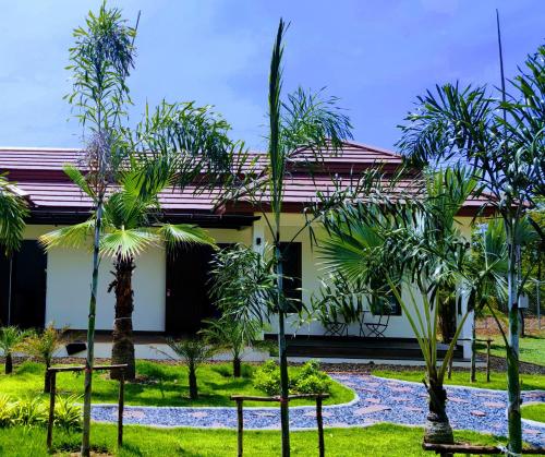a house with palm trees in front of it at Isan Golf & Adventure Hotel in Udon Thani