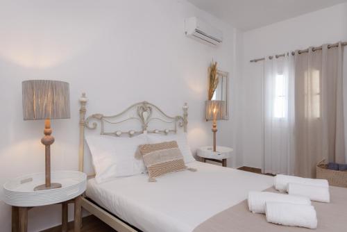 a bedroom with a white bed with two lamps and a chair at Miles Away Luxury Apartments in Platis Yialos Sifnos