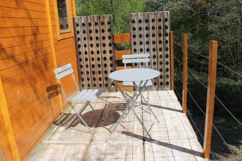 a patio with two chairs and a table and a fence at La Roulotte Viticole - sauna - toilette sèche in Floreffe