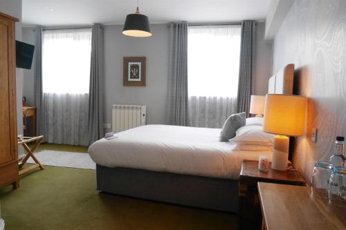 a bedroom with a bed and two windows at The Rose and Crown in Warwick