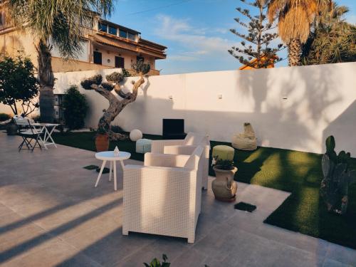 un patio con muebles blancos y una pared blanca en affittacamere Villa Masá en Zingarello