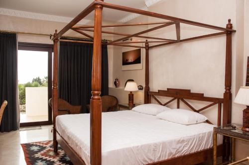 Hotel Villarocamar في ميخاس: غرفة نوم مع سرير خشبي ذو مظلة مع ملاءات بيضاء