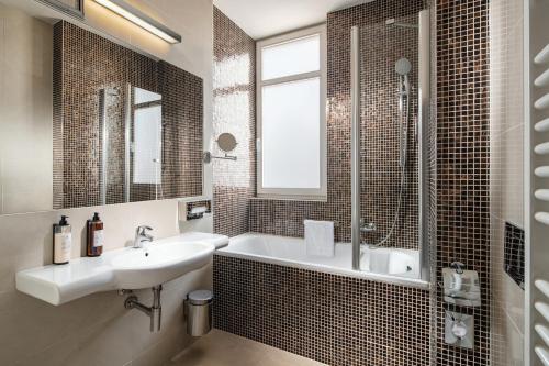 ein Bad mit einer Badewanne, einem Waschbecken und einer Dusche in der Unterkunft Clarion Hotel Prague Old Town in Prag