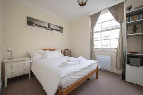 a bedroom with a bed with white sheets and a window at Unique and Cozy 1 Bed Flat in Dalston in London