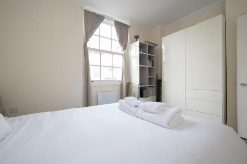 ein weißes Schlafzimmer mit weißen Handtüchern auf einem weißen Bett in der Unterkunft Unique and Cozy 1 Bed Flat in Dalston in London