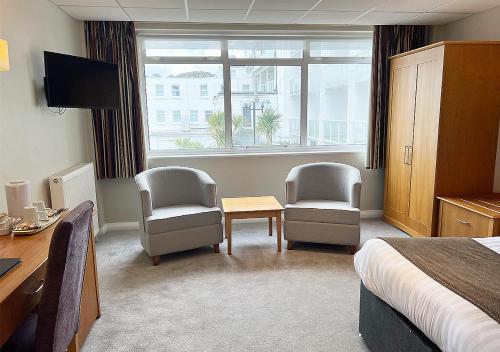 a hotel room with two chairs and a desk and a bed at Sandbanks Hotel in Poole