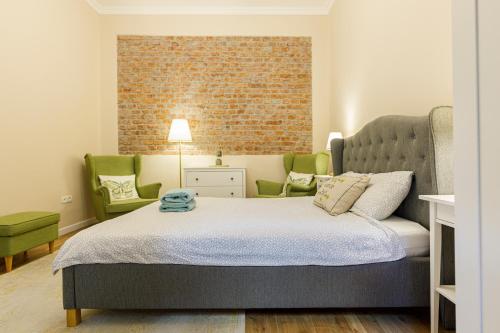 a bedroom with a bed and two green chairs at Beautiful Apartment in Heart of Historical Center in Timişoara
