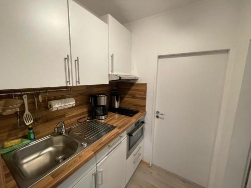 een keuken met witte kasten, een wastafel en een deur bij Ferienwohnung "Seemöwe" in Burgtiefe auf Fehmarn 