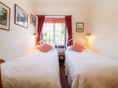 two beds in a room with a window at Magnolia Apartment in Bourton on the Water