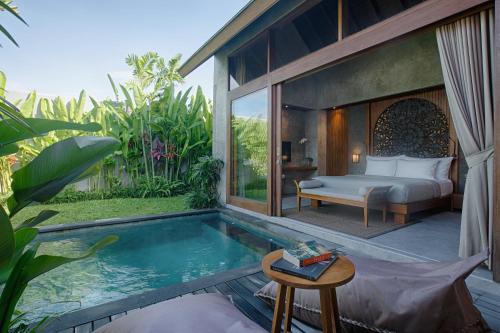 a bedroom with a bed and a swimming pool at Taman Dharmawangsa Suites in Nusa Dua