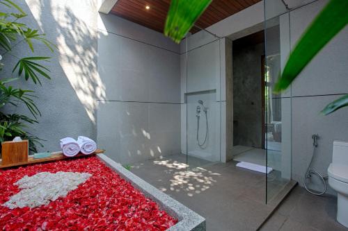 a bathroom with a shower and a red rug at Taman Dharmawangsa Suites in Nusa Dua