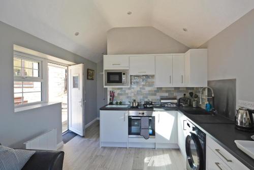 una cucina con armadi bianchi e piano cottura di Stylish ground floor conversion near Bath and Priston with outstanding views a Priston