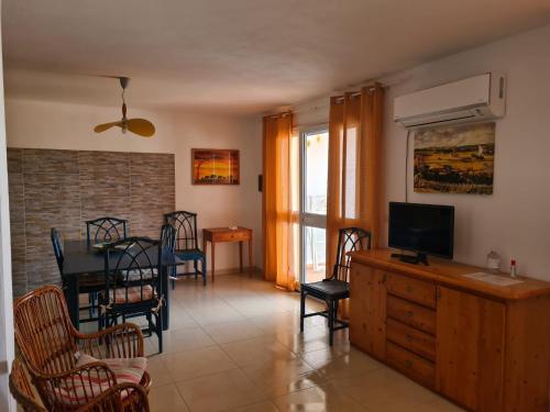- un salon avec une télévision, une table et des chaises dans l'établissement Casa Mare, à Santa Teresa Gallura