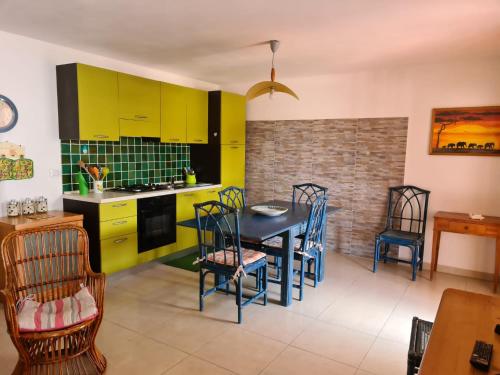 une cuisine avec des armoires jaunes, une table et des chaises dans l'établissement Casa Mare, à Santa Teresa Gallura