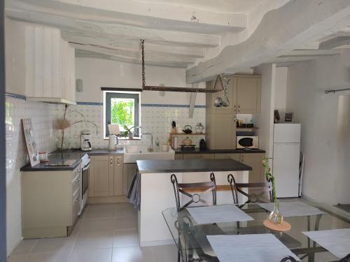 una cucina con elettrodomestici bianchi e un tavolo con sedie di Au Jardin de la Marquetterie a Cigogné
