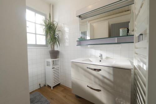 a white bathroom with a sink and a mirror at Charmante maison vendéenne à Saint Jean de Monts in Saint-Jean-de-Monts