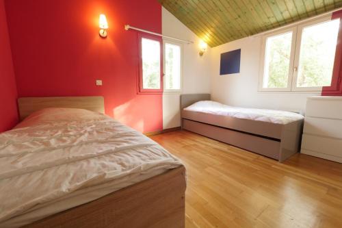 a bedroom with red walls and two beds in it at Villa avec piscine pour 8 in Saint-Jean-de-Monts