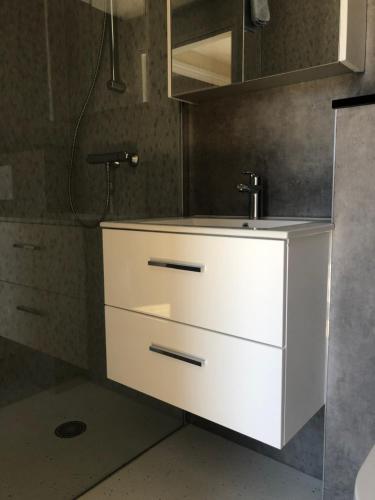 La salle de bains est pourvue d'un lavabo blanc et d'une douche. dans l'établissement Apartment " PENSCH ", à Wilwerwiltz