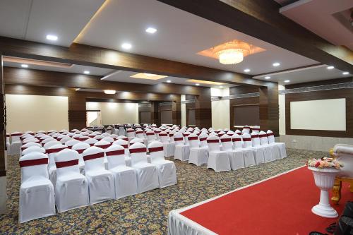 a room with rows of white chairs and a screen at Kyriad Hotel Pimpri in Pune