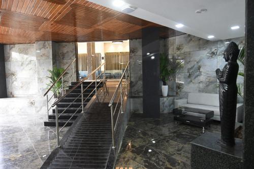 a lobby with a staircase with a statue in it at Kyriad Hotel Pimpri in Pune