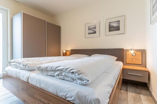 ein Schlafzimmer mit einem großen Bett mit weißer Bettwäsche in der Unterkunft Strandresidenz Dünenperle, App 6 in Kühlungsborn