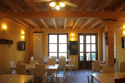 a dining room with tables and chairs and windows at Hostel Curavacas in Triollo