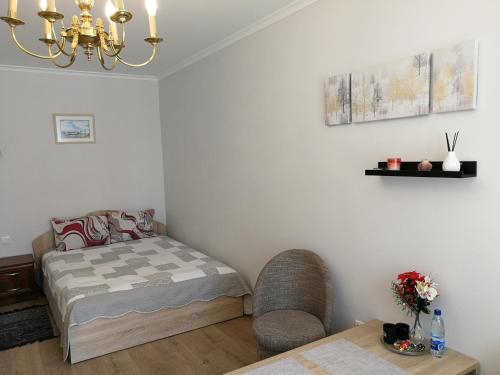 Un dormitorio con una cama, una silla y una mesa. en Šiauliai City Apartment, en Šiauliai